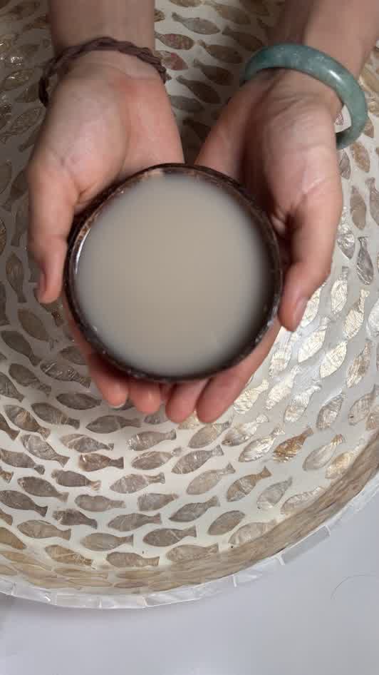 A coconut shell cup of Kava Nectar held in both hands